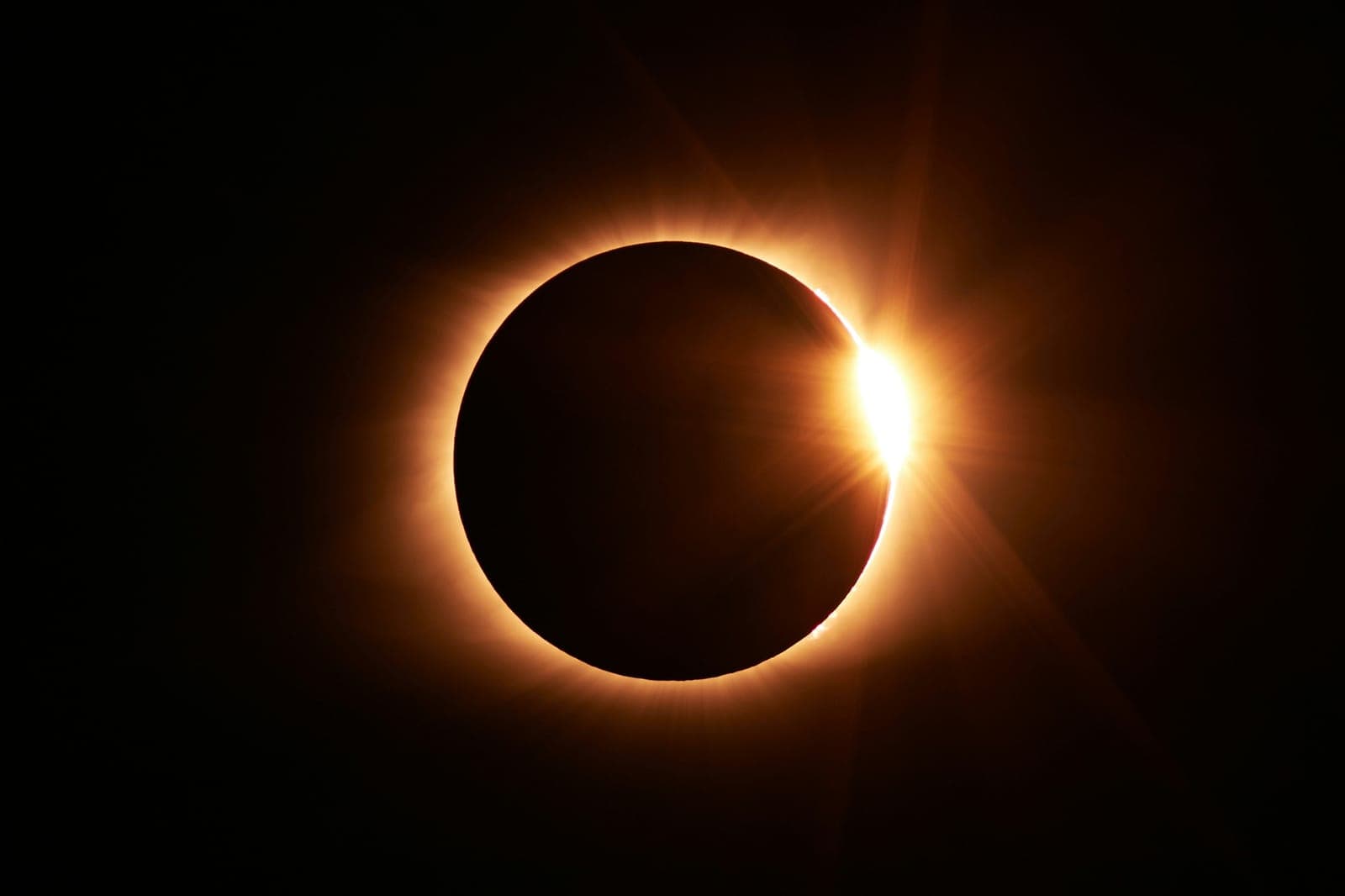 Totality during a solar eclipse, dark sky and corona over a landscape